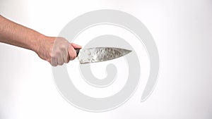 A hand with a knife on a white background. A man`s hand makes threatening movements with an old rusty knife