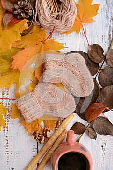 Hand-knitted brown baby socks, on white wooden background with autumn decorations