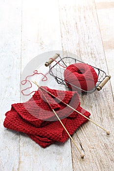 Hand knitted red scarf, yarn ball and knitting needles