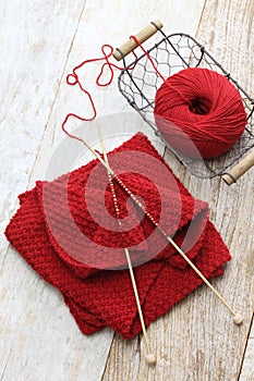 Hand knitted red scarf, yarn ball and knitting needles