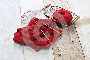 Hand knitted red scarf, yarn ball and knitting needles