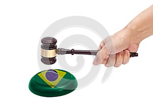 Hand knocking a Judge gavel at soundboard with Flag of Brazil