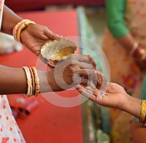 Hand of a lady offering Panchamrit to a devotee