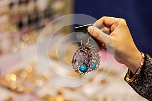 Hand of a lady selecting ear rings metal junk jewellery at a shop