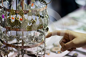 Hand of a lady selecting ear rings metal junk jewellery at a shop