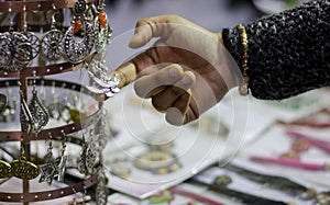 Hand of a lady selecting ear rings metal junk jewellery at a shop