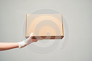 Hand in latex gloves holding cardboard box