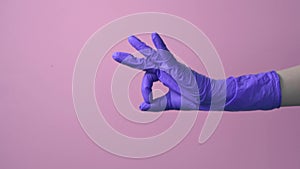 A hand in a latex medical glove makes an ok gesture. isolated