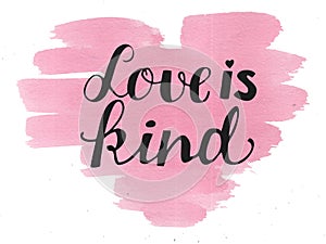 Hand lettering Love is kind made on watercolor background.