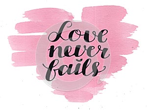 Hand lettering Love never fails made on watercolor background. photo