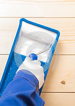 Hand in a light glove holds a roller and applies white impregnation to it, close-up