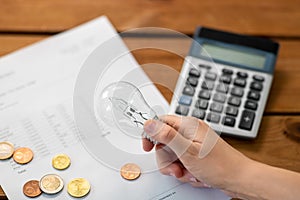 hand with lightbulb, bill, calculator and money