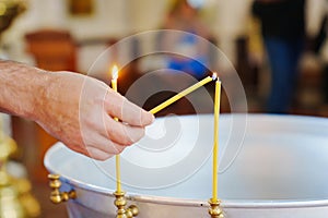 A hand lights a candle on a baptismal font in a church.