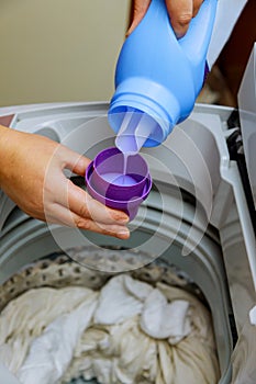 A hand with liquid detergent put into washing machine photo