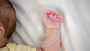 Hand of little baby on white sheet bed background. Cute boy and chubby hands