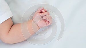 Hand of little baby on white sheet bed background. Cute boy and chubby hands