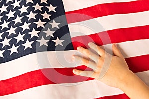 Hand of a little girl on the background of the American flag. The concept of patriotism