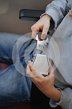 hand of a little girl fastens her seat belt in a seat on board the plane.