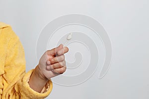 Hand of a little girl holding a cotton ear bud on a white background