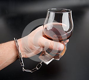 A hand locked to glass of alcohol