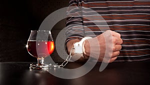 Hand locked to glass of alcohol