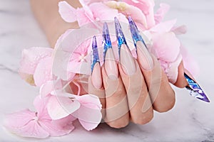 Hand with long artificial blue french manicured nails