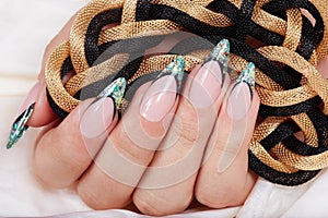 Hand with long artificial french manicured nails decorated with glitter