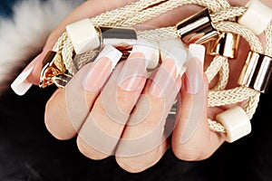 Hand with long artificial french manicured nails holding a necklace