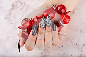 Hand with long artificial manicured nails colored with black nail polish