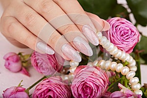 Hand with long artificial manicured nails colored with nail polish with silver glitter