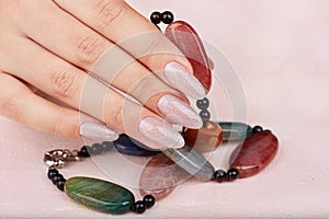 Hand with long artificial manicured nails colored with nail polish with silver glitter