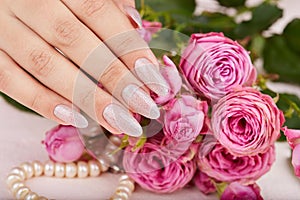 Hand with long artificial manicured nails colored with nail polish with silver glitter