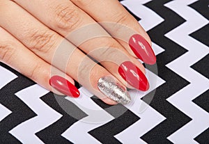 Hand with long artificial manicured nails colored with red nail polish