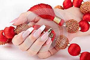 Hand with long artificial white and black french manicured nails and red necklace