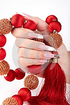 Hand with long artificial white and black french manicured nails and red necklace