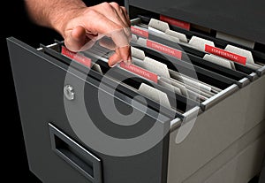 Hand Looking Though Filing Cabinet Drawer