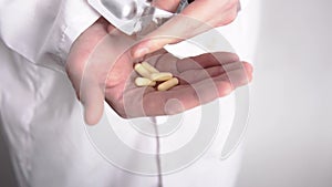 A hand with a lot of pills and a doctor who is getting them of from blister pack in close-up