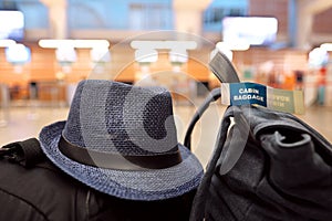 Hand luggage and a traveler`s hat on a bench at the airport