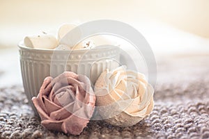 Hand-made from applesauce with natural marshmallow dyes in form of roses. cup of tea in background filled with light