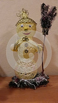 Snowman. Pale yellow color, made of thead with a broom in hand. photo