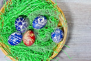 Hand made easter egg in green grass and basket on rustick wooden