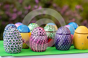 Hand-made Easter eggs on a green pedastal in front of purple lavender flowers