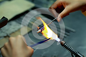 Artist of glass at work. Hand made glass beads in the fire out of red hot glowing glass for pandora bracelets,focus glass bead aro