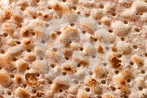 Hand-made matzah on Pesach holiday. Top view of flatbread matzo, macro, background