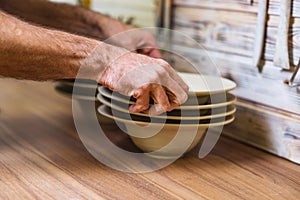 Hand made plates, bawls and tools on pottery studio table, shallow debt of field