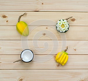 Hand made soap in the shape of tropic fruits bananas, flower and coconut on wooden background. Artificial fruits from Thailand.