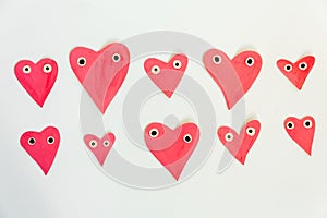 Hand made for Valentines or Mothers day. Hand-painted pink paper hearts with eyes on a white background. Flat lay. Space for text