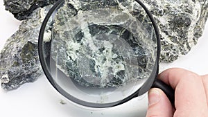 Hand with magnifying glass examines asbestos