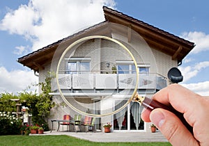 Hand with magnifying glass over house photo