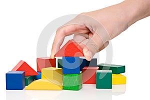 hand make a building of colored blocks.